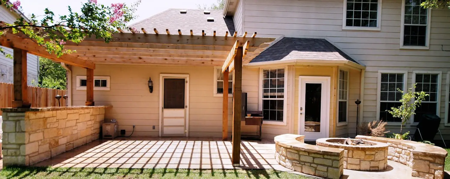 A patio with a fire pit and pergola in the back yard.