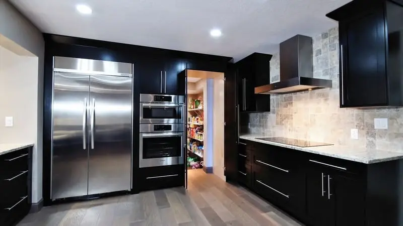 A kitchen with black cabinets and stainless steel appliances.