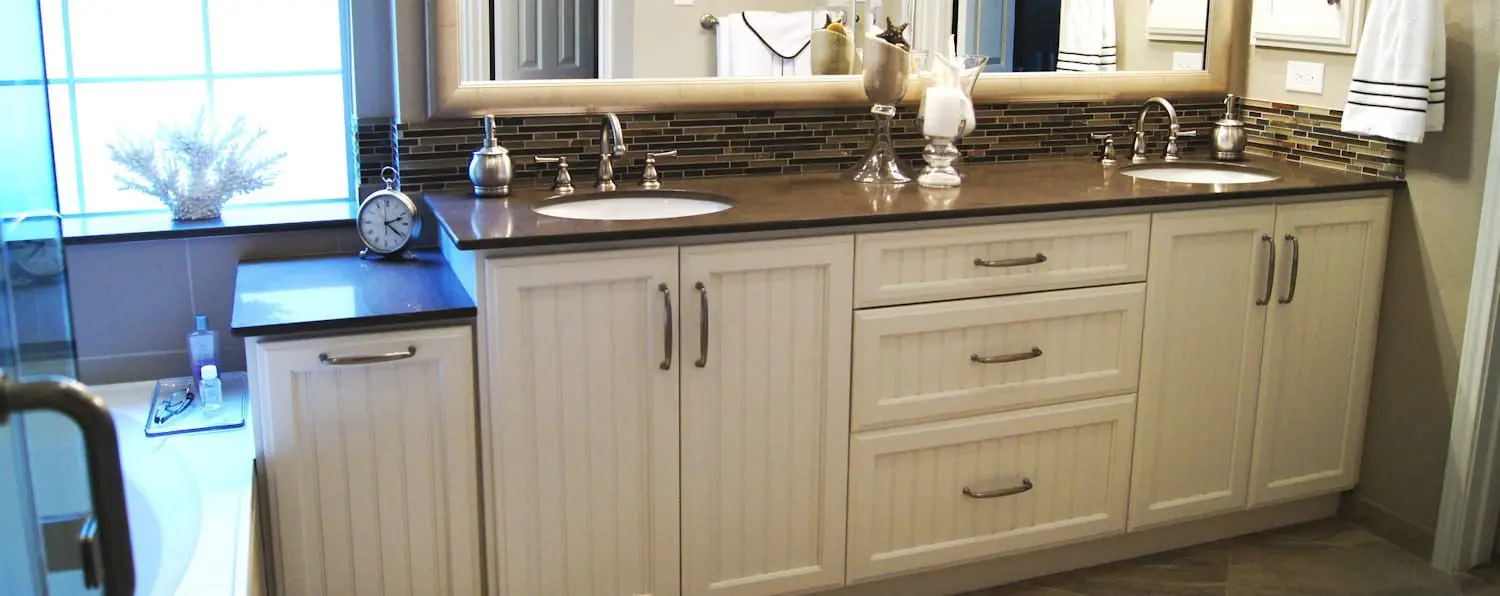 A bathroom with white cabinets and black counter tops.
