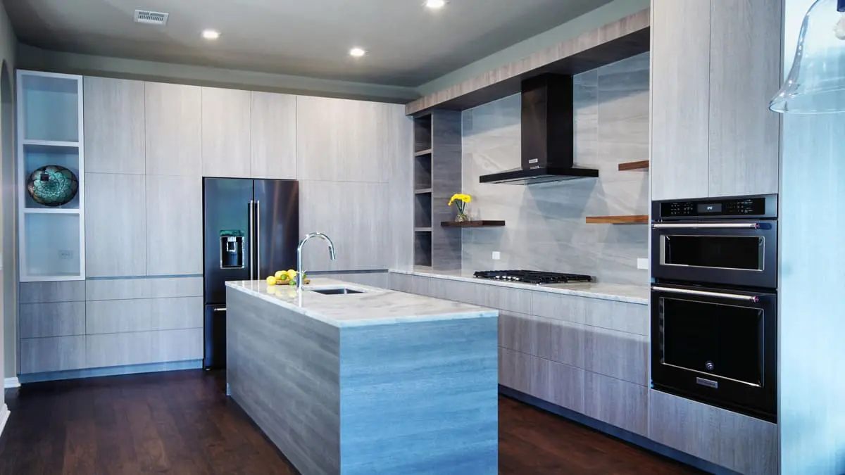 A kitchen with a refrigerator, oven and microwave.
