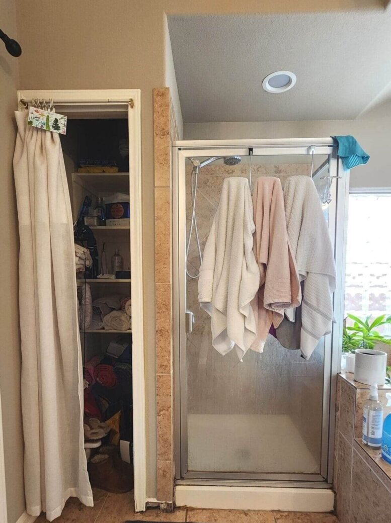 Bathroom with shower, towels, and storage closet.